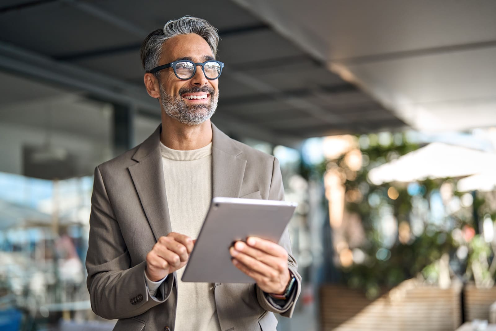 Asesor financiero con saco revisando información en una tableta, sonriendo
